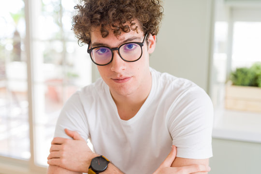 Young handsome man wearing glasses Relaxed with serious expression on face. Simple and natural with crossed arms