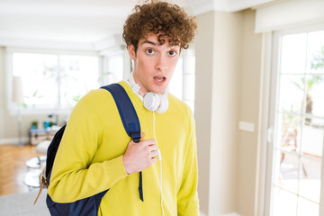 Young student man wearing headphones and backpack scared in shock with a surprise face, afraid and excited with fear expression