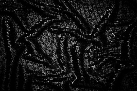 Metal glitter black cloth background, close up. Trendy Metallic dark fabric texture. Black sequins, sparkling sequined textile