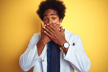 African american doctor man wearing stethoscope standing over isolated yellow background shocked covering mouth with hands for mistake. Secret concept.