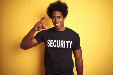 American safeguard man with afro hair wearing security uniform over isolated yellow background...