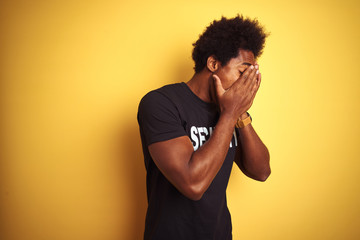 American safeguard man with afro hair wearing security uniform over isolated yellow background with sad expression covering face with hands while crying. Depression concept.
