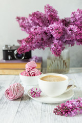 Bouquet of lilacs, cup of coffee, homemade marshmallow and stack of books Retro camera Selective focus