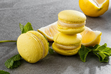 French macaroons isolated. Selective focus. Beautiful yellow macaroons with lemon and mint on gray stone background. Stylish arrangement sweet. Flat lay, top view. Macro photo.