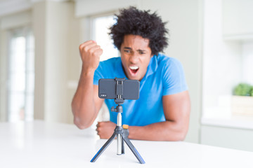 African American man doing online call with webcam using smartphone annoyed and frustrated shouting with anger, crazy and yelling with raised hand, anger concept