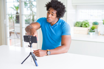 Fototapeta premium African American man doing online call with webcam using smartphone pointing with finger to the camera and to you, hand sign, positive and confident gesture from the front