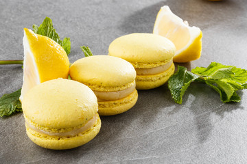 French macaroons isolated. Selective focus. Beautiful yellow macaroons with lemon and mint on gray stone background. Stylish arrangement sweet. Flat lay, top view. Macro photo.