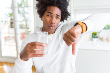 African American man drinking a glass of water at home with angry face, negative sign showing...