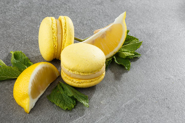 French macaroons isolated. Selective focus. Beautiful yellow macaroons with lemon and mint on gray stone background. Stylish arrangement sweet. Flat lay, top view. Macro photo.