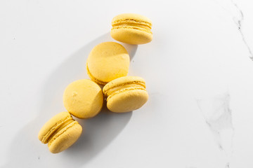 French macaroons isolated. Selective focus. Beautiful yellow macaroons on marble background. Stylish arrangement sweet. Flat lay, top view. Macro photo. With copy space.