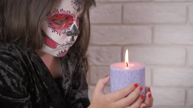 Horror at Halloween day. Little girl in scary makeup with a burning candle. Halloween child.