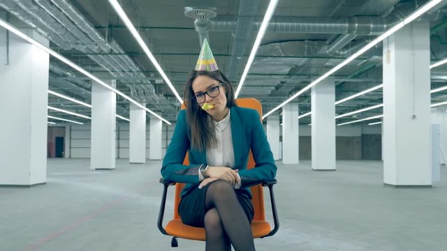 Boring party concept. Sad female manager in a birthday hat is sitting in a rolling chair