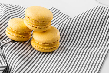 French macaroons isolated. Selective focus. Beautiful yellow macaroons on striped napkin background. Stylish arrangement sweet. Flat lay, top view. Macro photo.