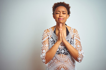 Young african american woman with afro hair wearing a bikini over white isolated background begging and praying with hands together with hope expression on face very emotional and worried. 