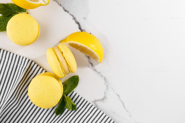French macaroons isolated. Selective focus. Beautiful yellow macaroons with mint and lemon in striped napkin on marble background. Stylish arrangement sweet. Flat lay, Macro photo. With copy space.