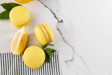 French macaroons isolated. Selective focus. Beautiful yellow macaroons with mint and lemon in striped napkin on marble background. Stylish arrangement sweet. Flat lay, Macro photo. With copy space.