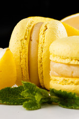 French macaroons isolated. Selective focus. Beautiful yellow macaroons with mint on marble background. Stylish arrangement sweet. Flat lay, top view. Macro photo.