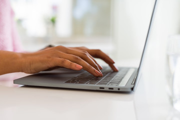 Close up of young woman working typing using laptop