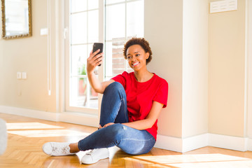 Beautiful young african american woman sitting on the floor taking a selfie smiling