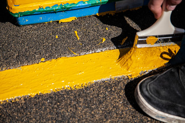 Paint brush. Man paints objects in the yard. Work with color. It's time to upgrade the garden.