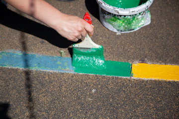Paint brush. Man paints objects in the yard. Work with color. It's time to upgrade the garden.
