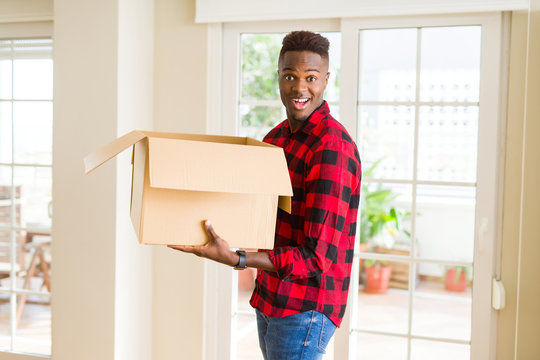 Young african american man holding a carton box, packing cardboard delivery package at home
