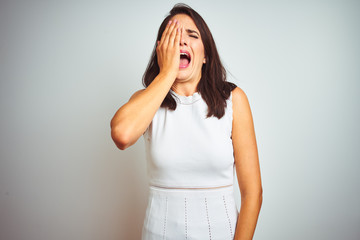 Young beautiful woman wearing dress standing over white isolated background Yawning tired covering half face, eye and mouth with hand. Face hurts in pain.