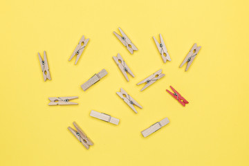 Small wooden clothespins on a bright yellow colored background. Top view.