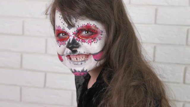 Horror at Halloween day. A little girl in a scary make-up gets angry, showing her teeth. Halloween child.