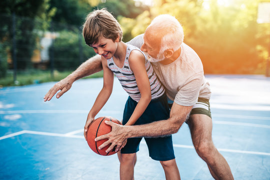 Grandfather And His Grandson Playing Basketball.