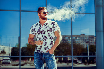 Men with beard vaping outdoor in sunglasses, focus on steam.