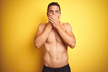 Fototapeta premium Young handsome shirtless man over isolated yellow background shocked covering mouth with hands for mistake. Secret concept.
