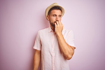 Handsome man wearing hat and summer shirt over pink isolated background looking stressed and...