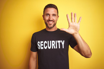 Young safeguard man wearing security uniform over yellow isolated background showing and pointing...