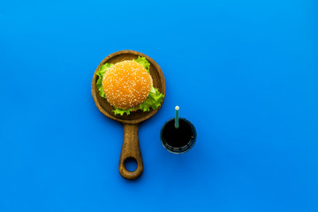 Traditional american food concept with burger on pan and drink on blue background top view