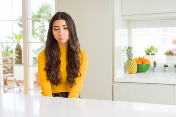 Young beautiful woman at home on white table depressed and worry for distress, crying angry and afraid. Sad expression.