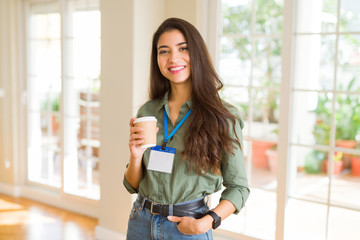 Beautiful young business woman wearing id card and drinking a cup coffee