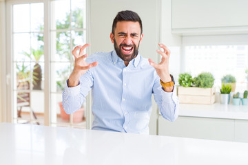 Handsome hispanic business man Shouting frustrated with rage, hands trying to strangle, yelling mad