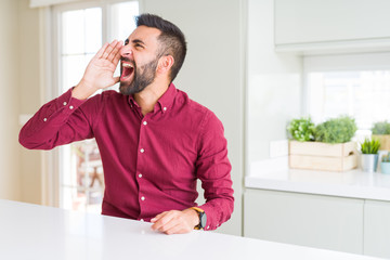 Handsome hispanic business man shouting and screaming loud to side with hand on mouth. Communication concept.