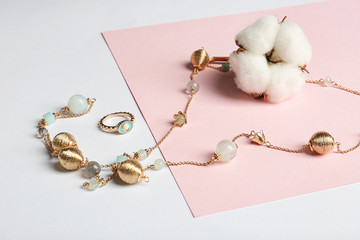 Elegant jewelry and cotton flower on color background