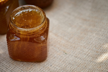 Herbal honey in jar with dipper.  Honey in glass jars and honeycombs wax on stone background