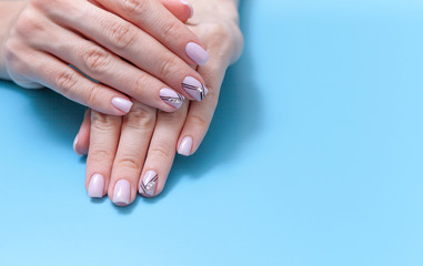 Fototapeta premium Fashionable feminine art, beautiful unique nail manicure on a blue background