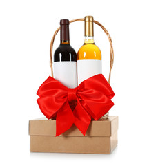 Festive basket with bottles of wine and gift box on white background