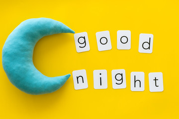Good night text and moon for sleep concept on yellow background top view