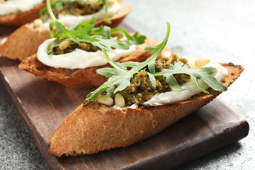 Serving board with tasty bruschettas on grey table, closeup