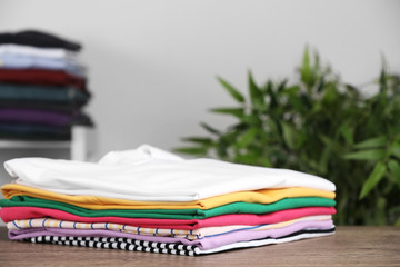 Pile of ironed clothes on table in room. Space for text