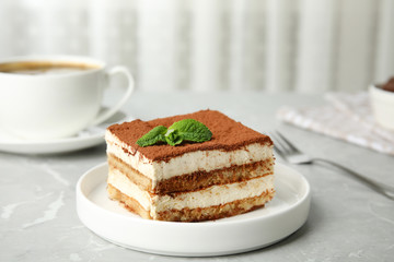 Delicious tiramisu cake with cup on table
