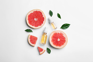 Composition with grapefruit slices and bottles of essential oil on white background, top view