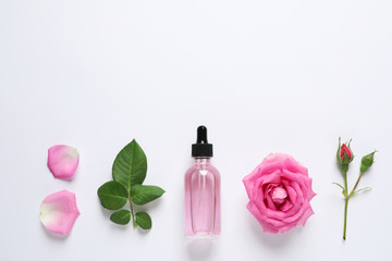 Composition with rose essential oil and flowers on white background, top view