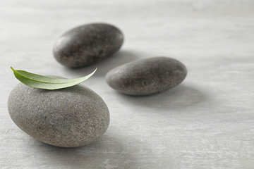 Fototapeta na wymiar Spa stones with green leaf on grey background. Space for text